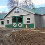 green and gray pole barn with windows and large doors