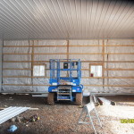 insulation being installed within a pole barn
