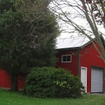 red pole barn behind trees
